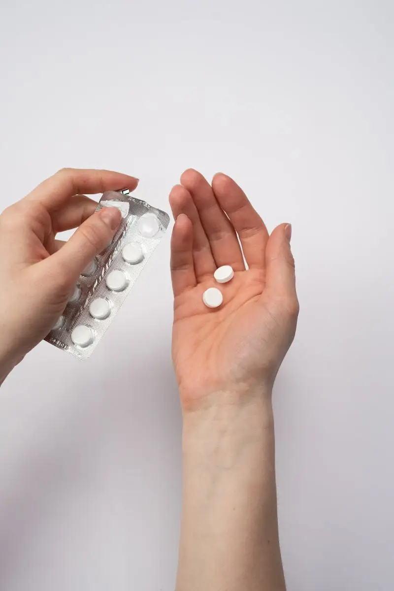 A person's hands holding white pills, symbolizing health and medication care.